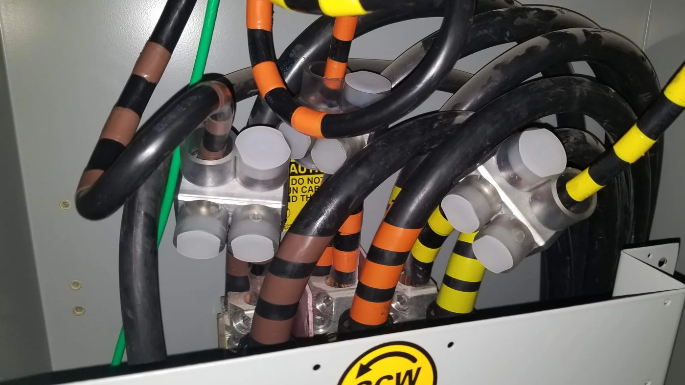 Service conductors landed on lugs with coloured phase tape inside a distribution enclosure