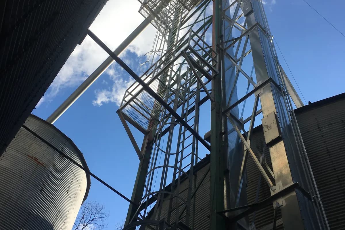 Steel grain bins and an elevator leg seen from below