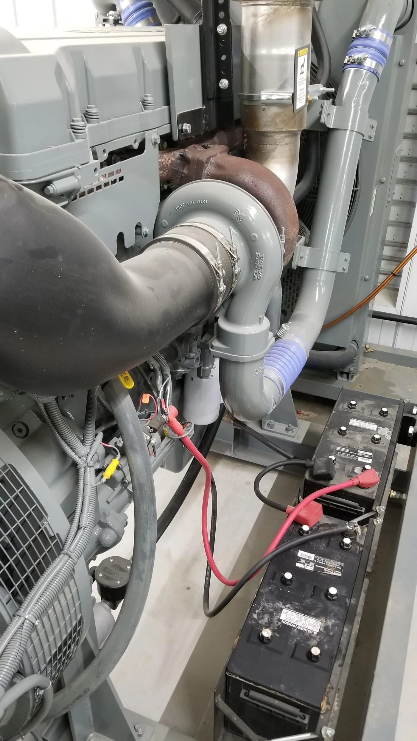 Standby generator set with battery connections and exhaust in a generator room